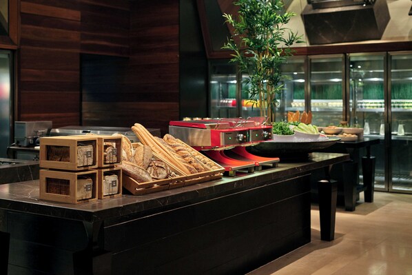 A bakery counter with bread and pastries, a red appliance, and a plant. - Grand Hyatt Melbourne (Melbourne)
