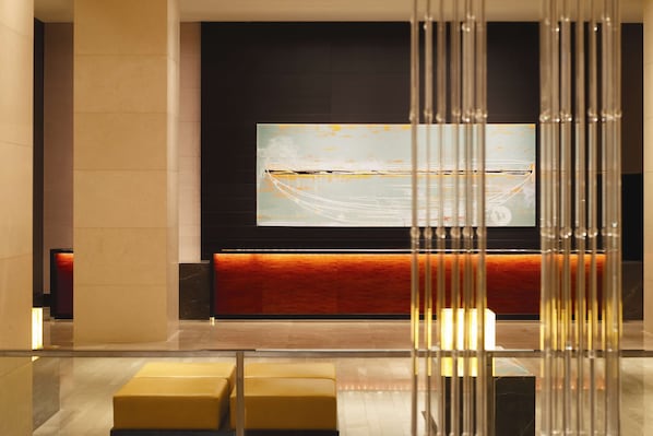 A modern lobby with a large abstract painting, a reception desk, and a seating area with yellow chairs.