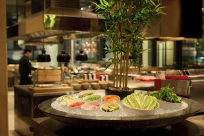 A buffet with various food items and a decorative bamboo plant. - Grand Hyatt Melbourne (Melbourne)