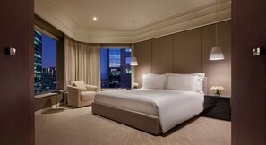 A modern hotel bedroom with a large bed, a sitting area, and a view of the cityscape. - Grand Hyatt Melbourne (Melbourne)