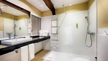 A modern bathroom with a large mirror, two sinks, a shower, and a bathtub.