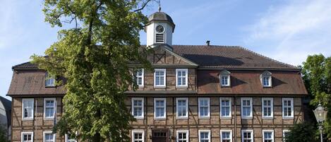 A historic building with a clock tower, multiple windows, and a cobblestone street.