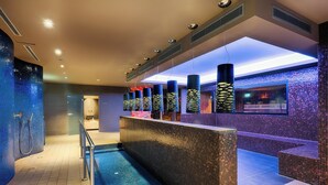 A modern bathroom with a large pool, a seating area, and a reception desk.