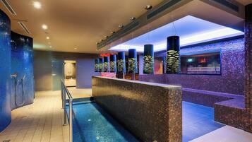 Relax by the pool in this serene oasis, featuring a large pool area surrounded by a mosaic tile floor and a long bench.