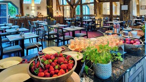A restaurant with wooden beams, tables, chairs, and a variety of food and drink items on the counter.