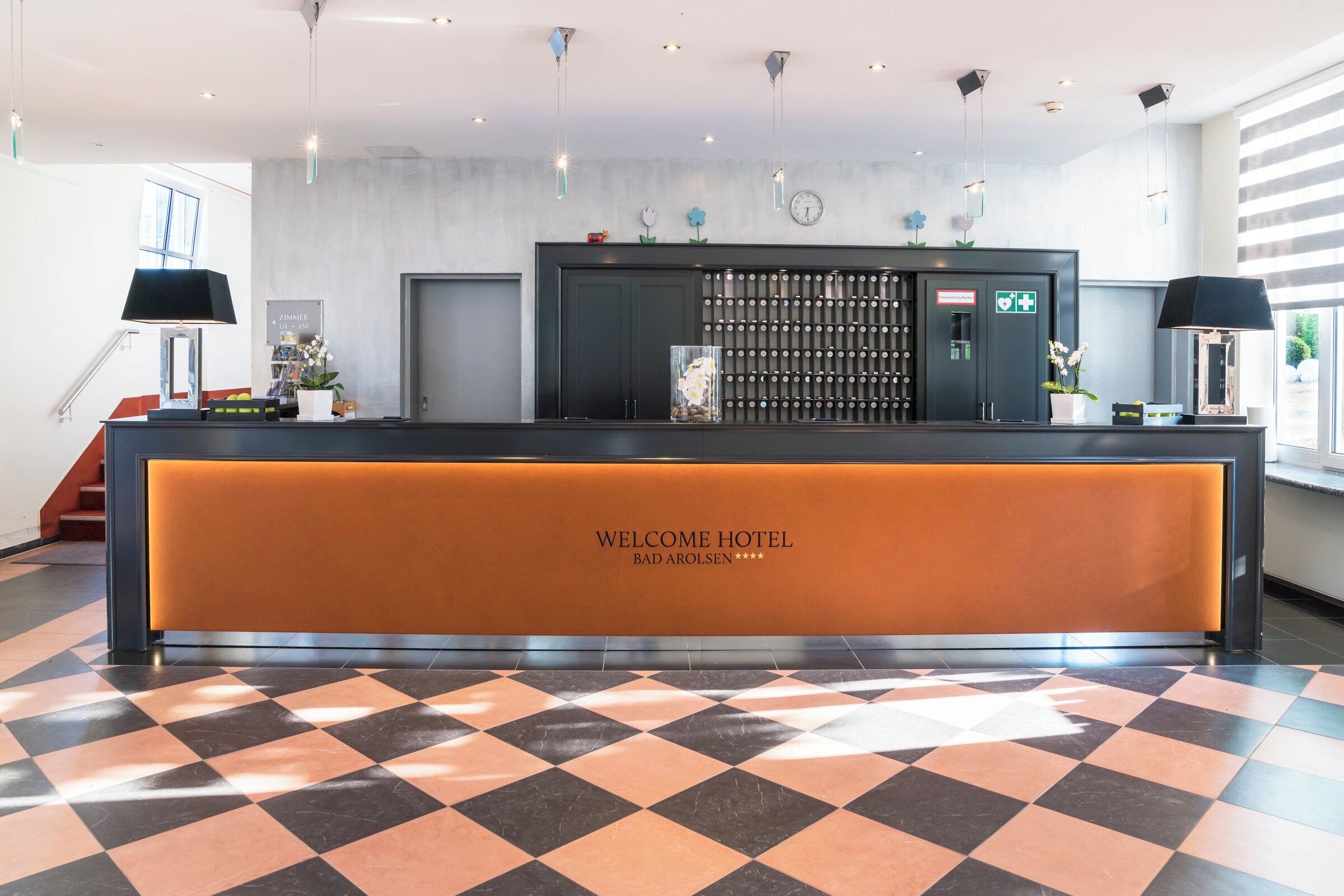 A reception area with a checkered floor, a reception desk, and a wall-mounted clock.