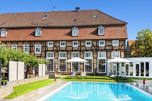 A traditional half-timbered building with a swimming pool and outdoor seating.