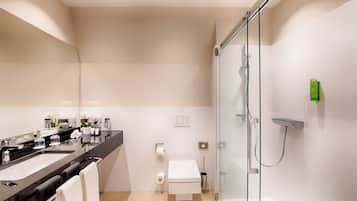 A modern bathroom with a glass-enclosed shower, a black countertop sink, and a toilet.
