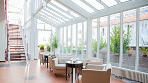 A spacious indoor area with a glass ceiling, comfortable seating, and a view of the outside.
