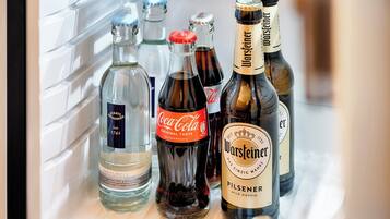 A refrigerator stocked with various beverages including Coca-Cola, Warsteiner beer, and other drinks.