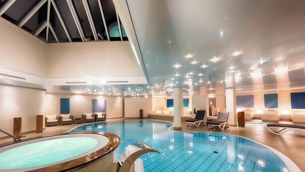 A large indoor swimming pool with multiple seating areas and a separate hot tub.