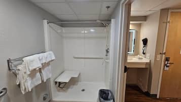 Un baño con ducha, perchero, lavabo y cubo de basura.