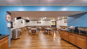 Un restaurante con mesas y sillas de madera, un mostrador de buffet y un reloj en la pared.