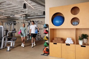 A gym with exercise equipment, a wall with exercise balls, and a shelf with towels and water bottles. - Avatar Hotel Santa Clara, Tapestry Collection by Hilton (Santa Clara)