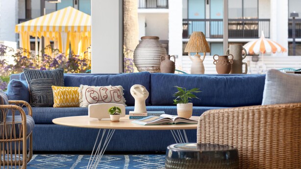 A modern living room with a blue sofa, wicker chairs, a round coffee table, and decorative items. - Avatar Hotel Santa Clara, Tapestry Collection by Hilton (Santa Clara)