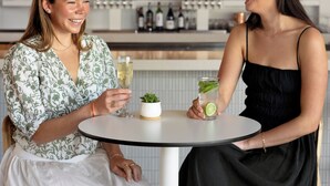 Two people seated at a round table with drinks, a bar in the background, and a modern interior design. - Avatar Hotel Santa Clara, Tapestry Collection by Hilton (Santa Clara)