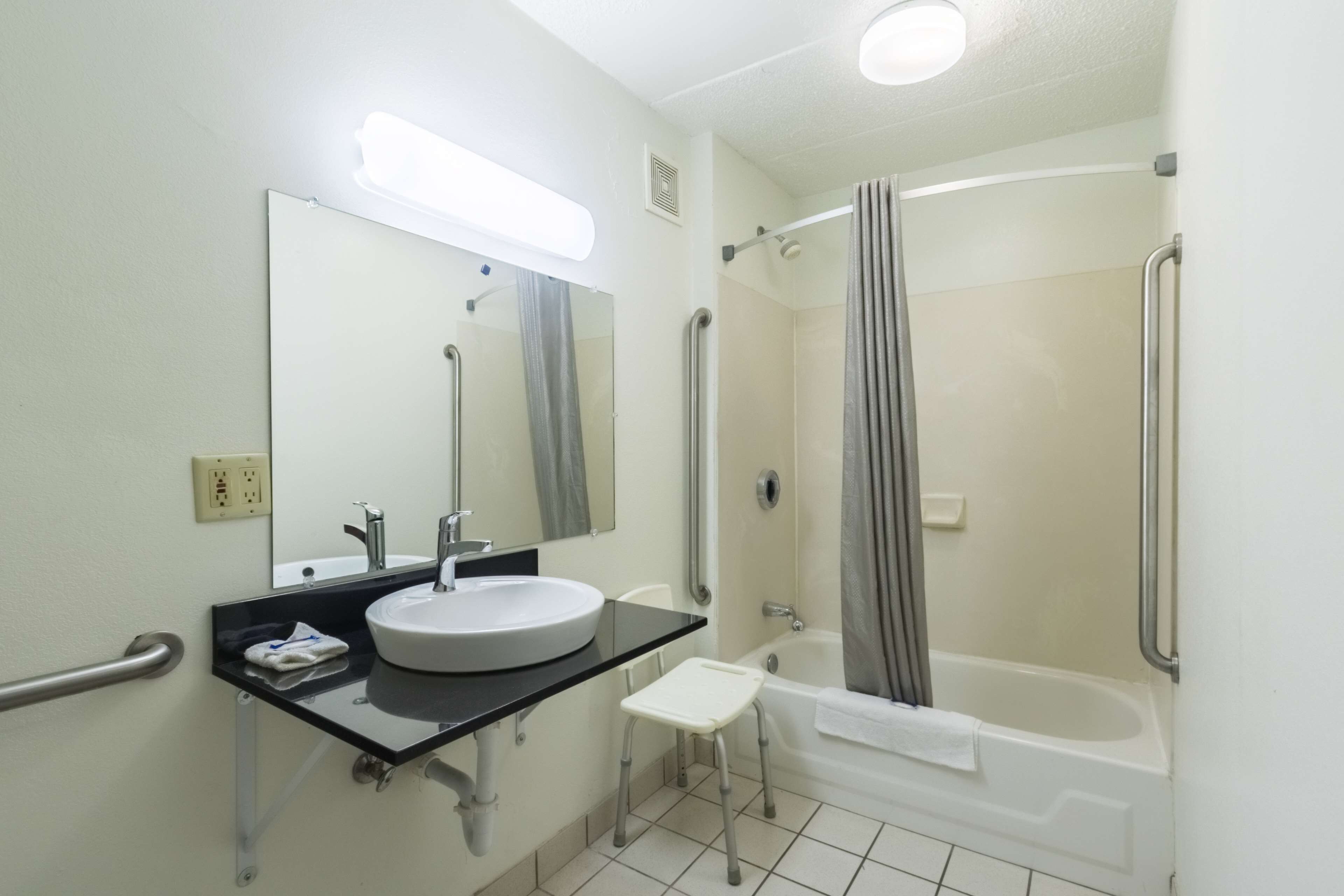 A bathroom with a sink, mirror, and bathtub.