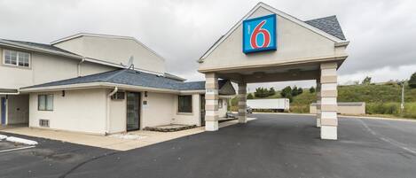 A motel with a '6' sign, a covered parking area, and a building with a grey roof.