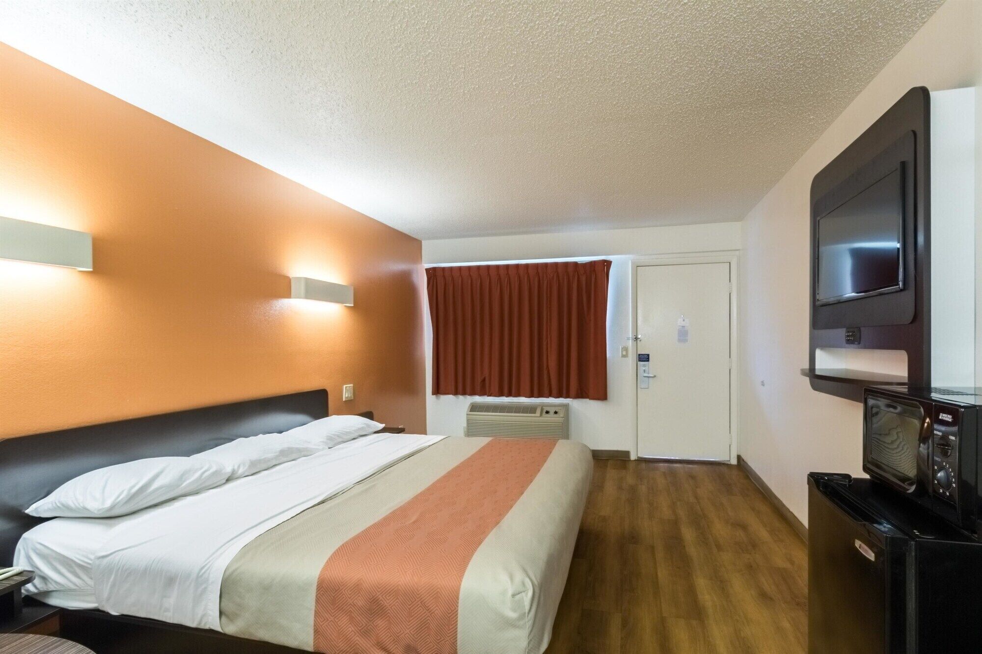 A hotel room with a bed, a television, and a heater.