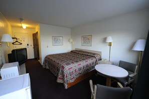 Enjoy a comfortable stay in this well-appointed room featuring a neatly made bed, a desk, and a small table with chair.