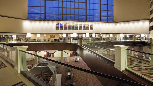 A spacious hotel atrium with multiple levels, a central staircase, and a large glass ceiling allowing natural light. - Sonesta Hotel Houston IAH Airport (Houston)