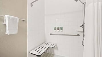 A white bathroom with a shower, a grab bar, and a towel rack.