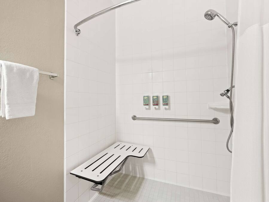 A white bathroom with a shower, a grab bar, and a towel rack.