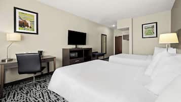 A hotel room with a large bed, a desk with a chair, a TV, and two wall-mounted lamps.