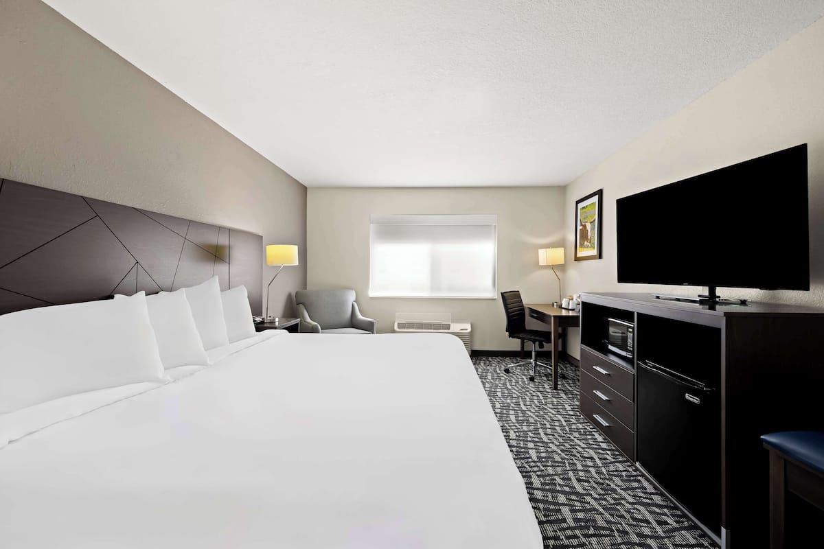 A hotel room with a large bed, a desk, a television, and a wardrobe.