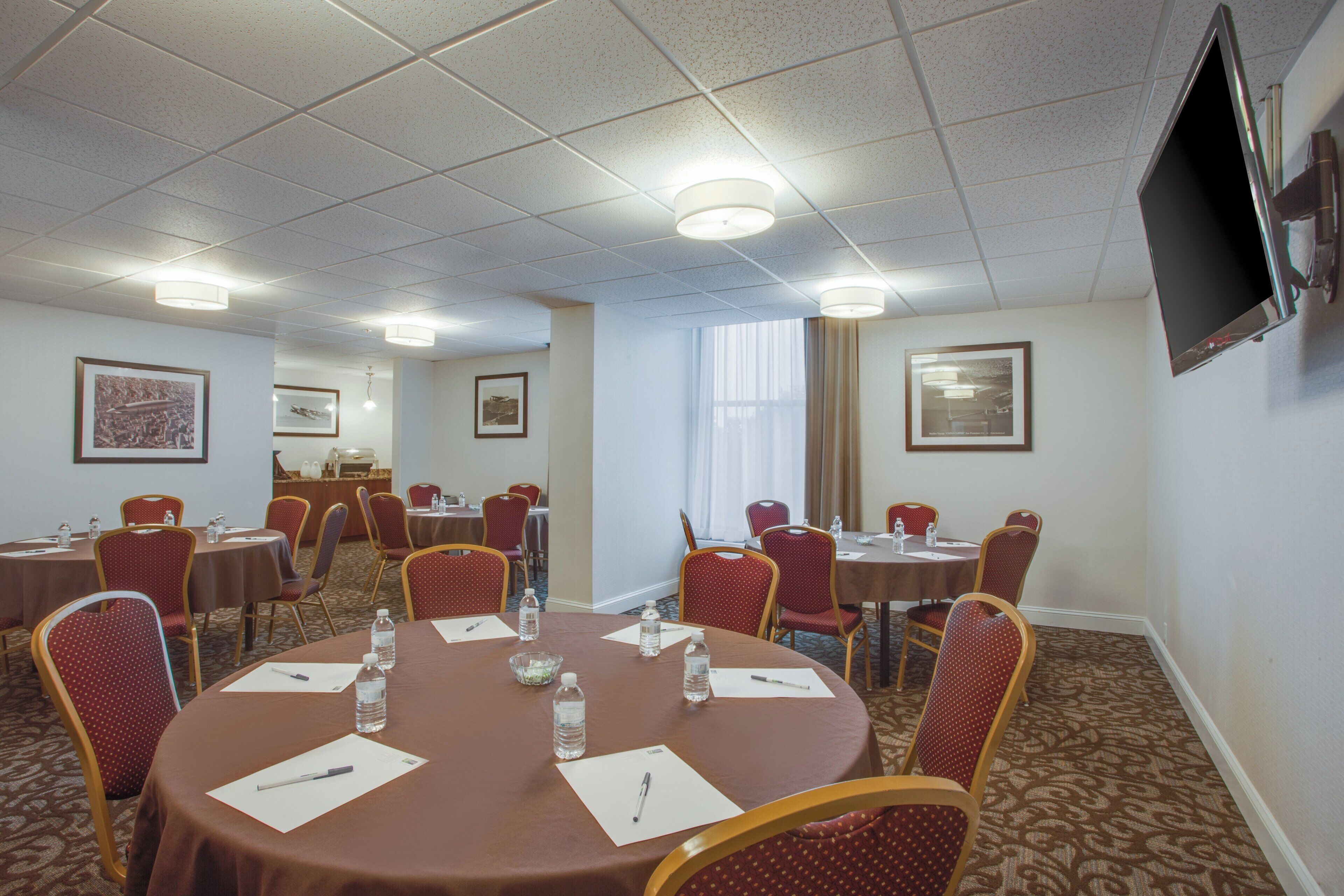 A conference room with round tables, chairs, water bottles, and papers.