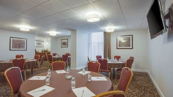 A conference room with round tables, chairs, water bottles, and papers.
