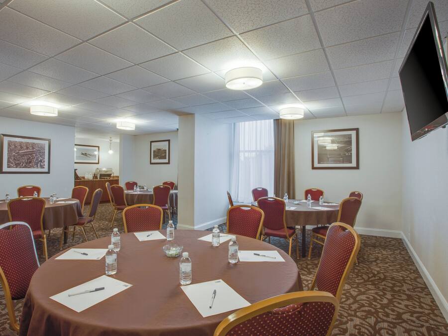 A conference room with round tables, chairs, water bottles, and papers.