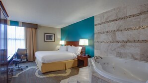 A hotel room with a large bed, a desk, a chair, a desk lamp, a nightstand, and a bathtub. - Holiday Inn Express Washington DC East - Andrews AFB by IHG (Suitland)