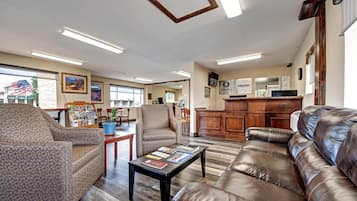 A spacious lobby with leather sofas, a coffee table, and a reception desk.