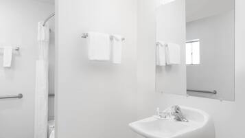 Un baño moderno con un lavamanos blanco, un espejo y dos toallas colgadas en toalleros.