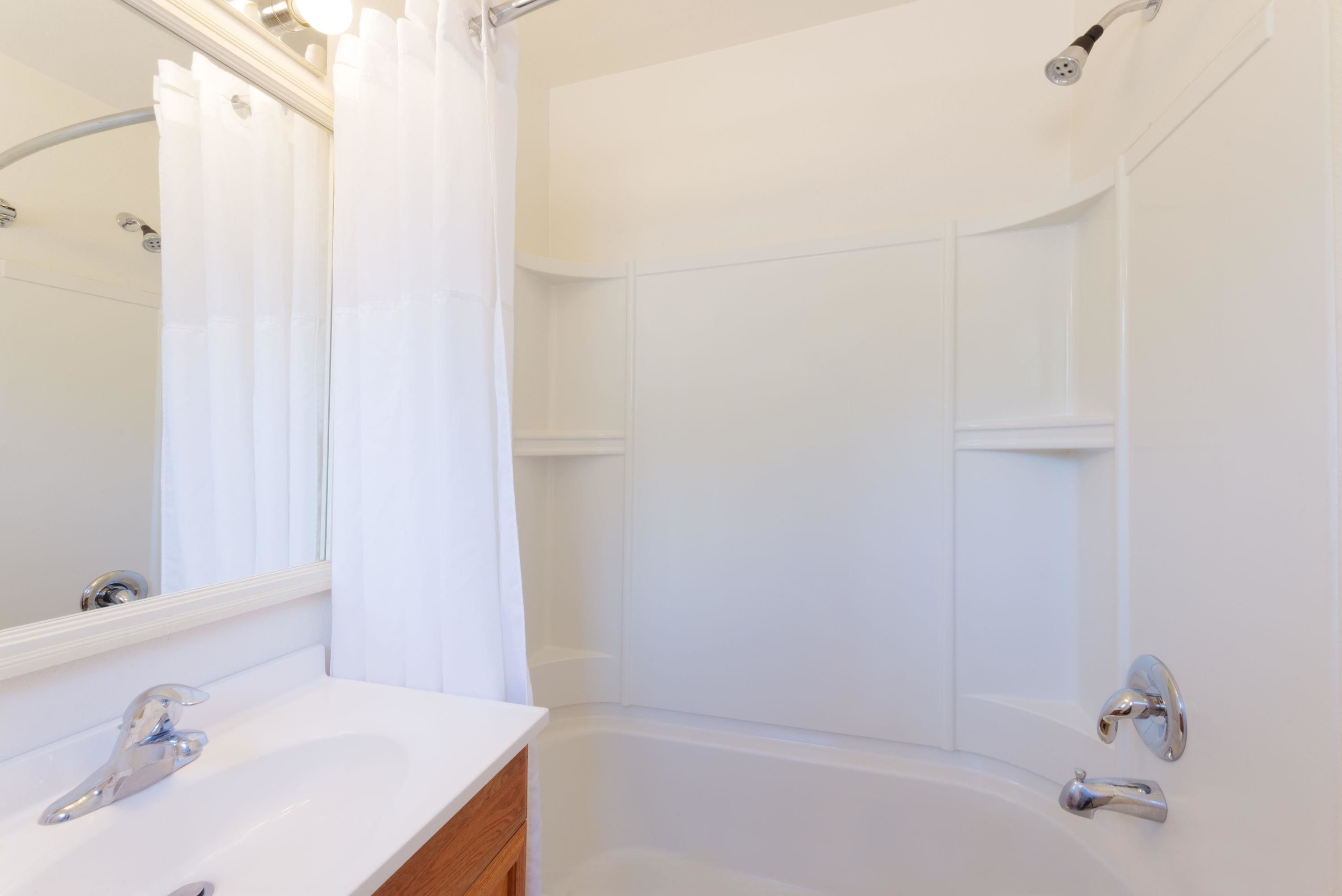 A modern bathroom with a white sink, mirror, and shower.