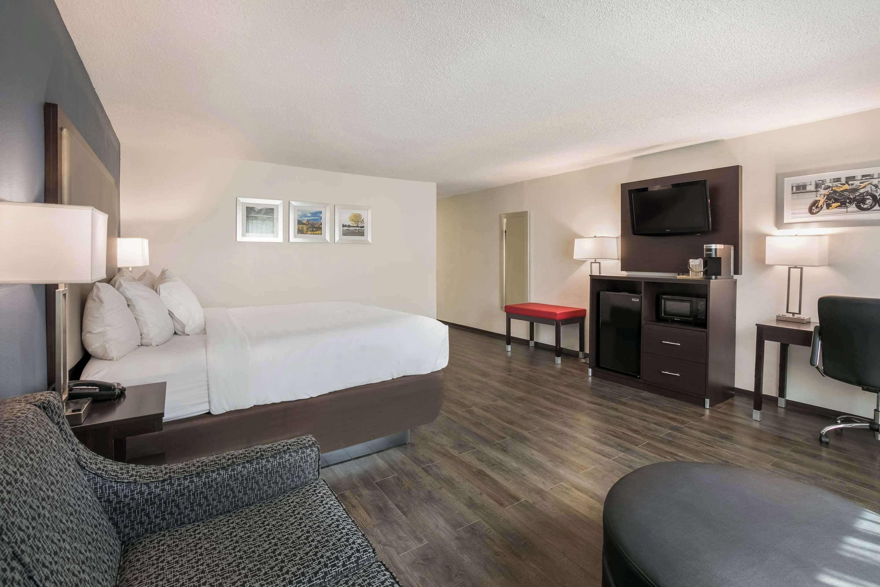 Une chambre d’hôtel avec un lit, un bureau, une télévision et une chaise.