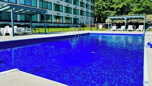 Une piscine rectangulaire à l’eau d’un bleu limpide, entourée d’une terrasse en béton.