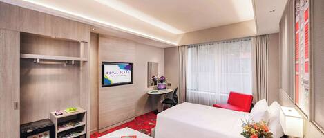 Habitación de hotel con dos camas, un escritorio con una computadora portátil, refrigerador, minibar y un ventanal con cortinas.