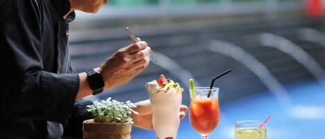 A person dining at a table with various dishes, including a milkshake, a cocktail, and a plate of food.