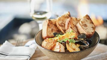 Un bol de mariscos con pan sobre una mesa de madera.