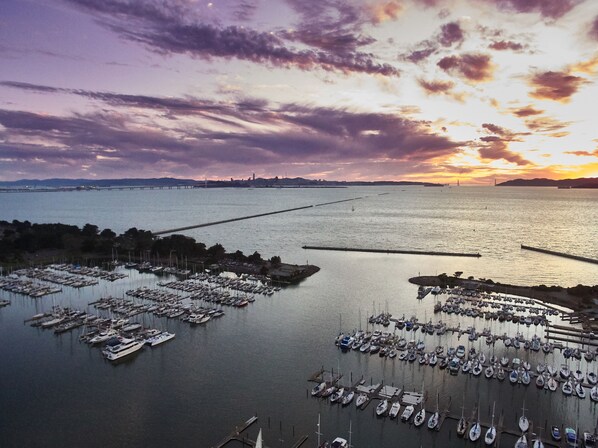 A marina with numerous boats docked, a large body of water, and a distant city skyline during sunset. - DoubleTree by Hilton Hotel Berkeley Marina (Berkeley)