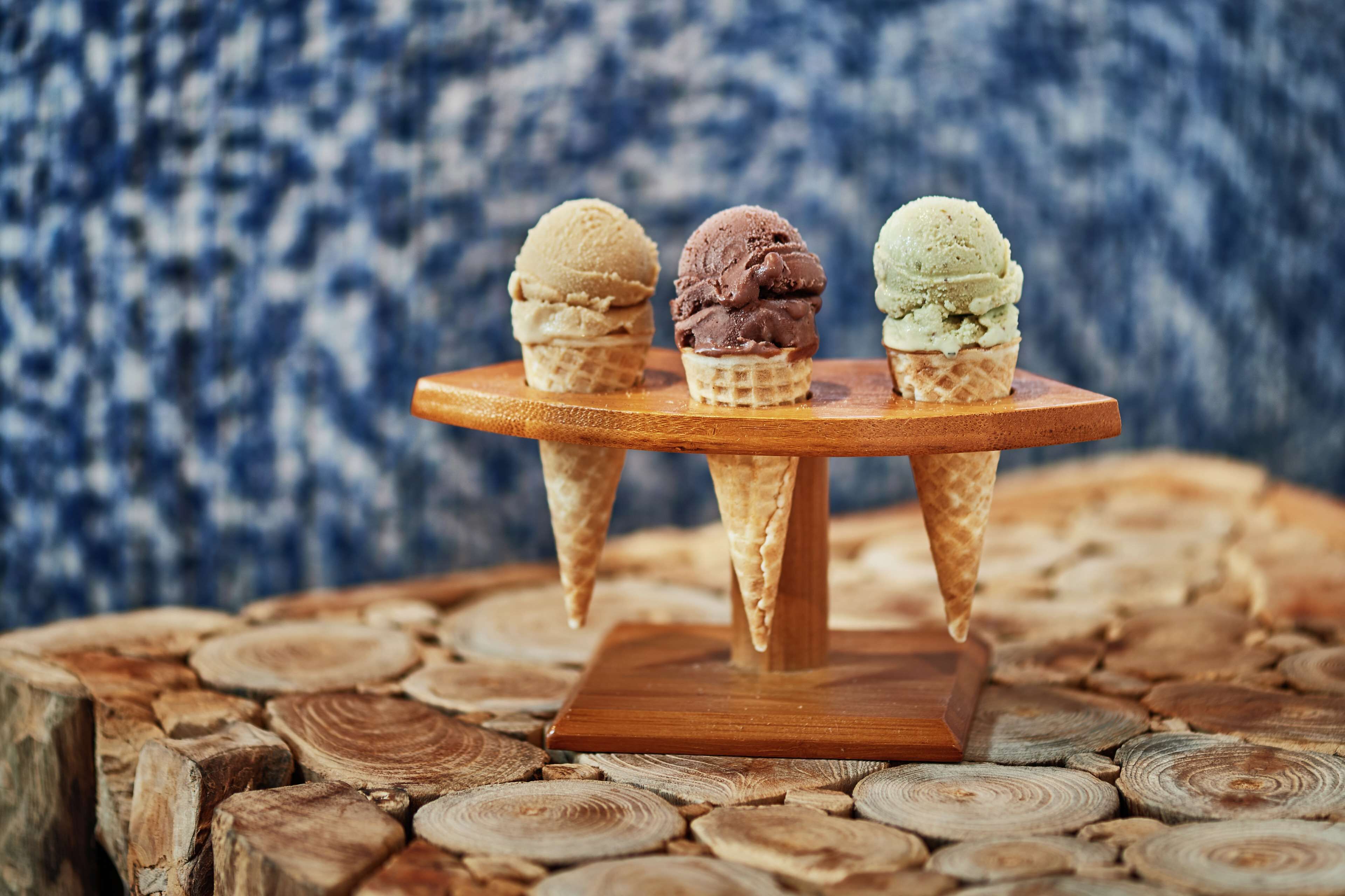 Three ice cream cones on a wooden stand.
