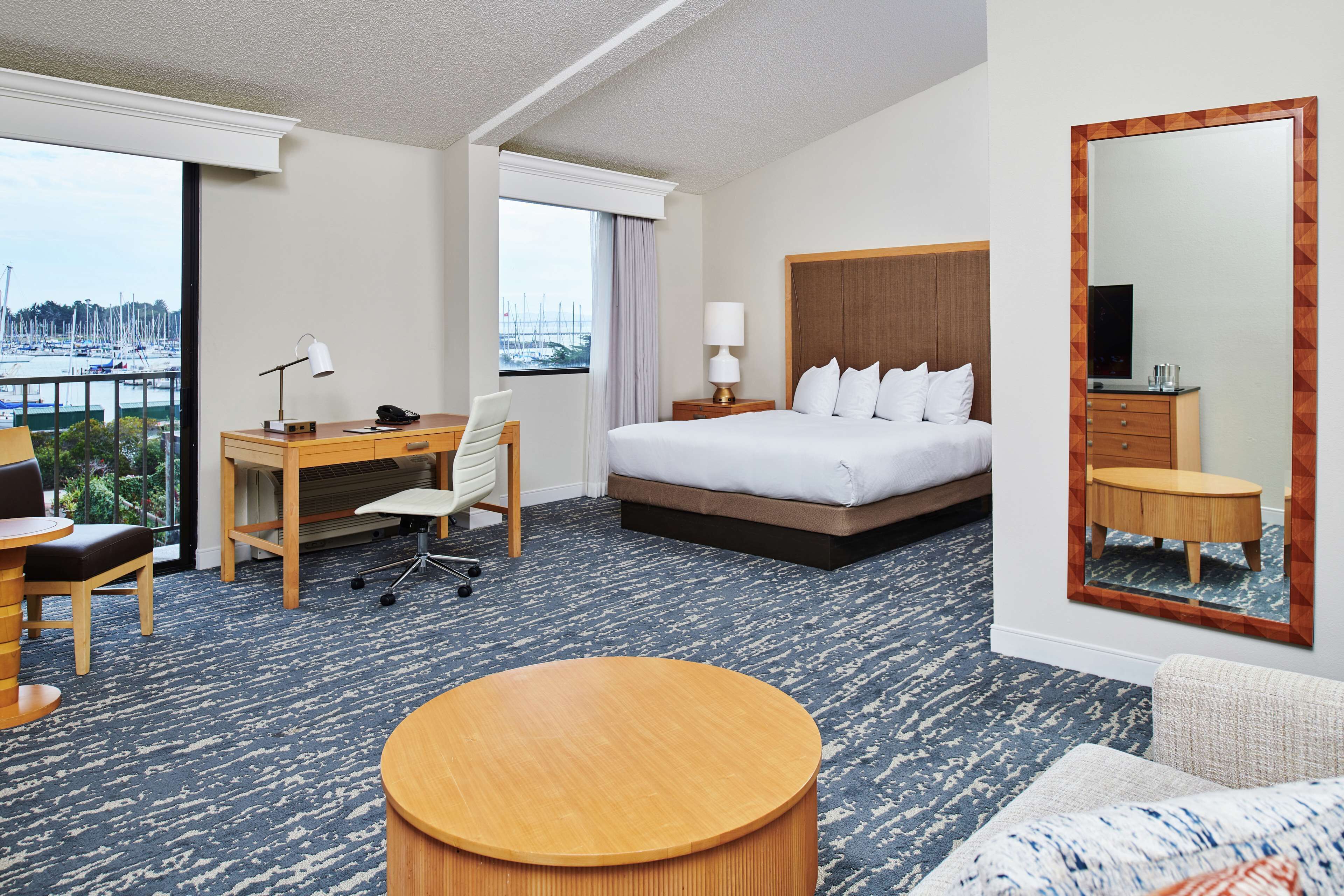 A hotel room with a bed, desk, chair, and a round table.