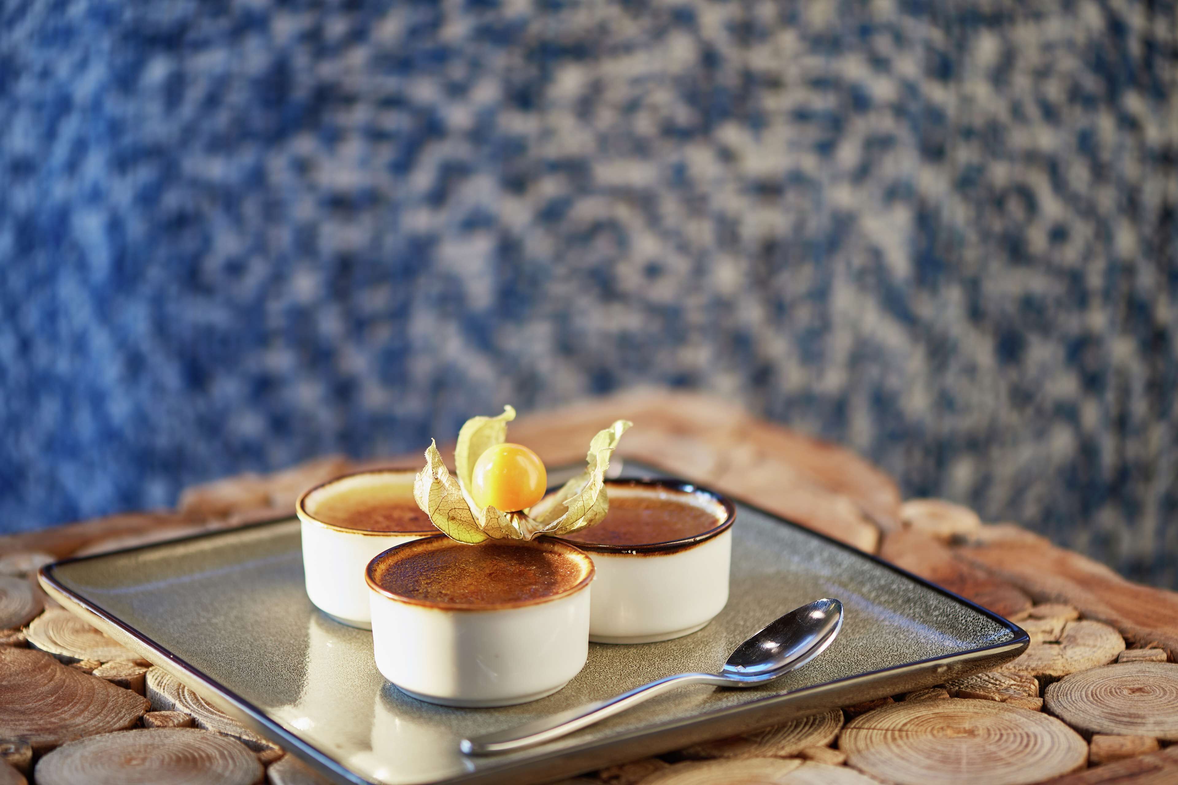 Two dessert cups on a tray with a spoon, set on a wooden surface.