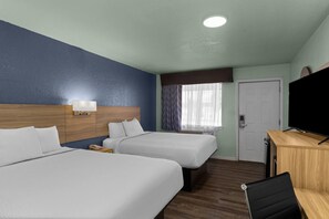 Habitación de hotel con dos camas, un escritorio, un televisor y una ventana con cortinas.