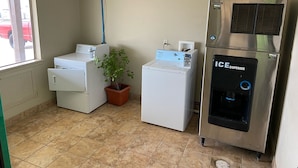 Un lavadero con una lavadora blanca, una secadora blanca y un dispensador de hielo.