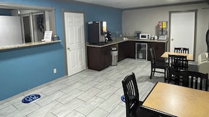 Cocina compacta equipada con microondas, refrigerador y lavamanos. Cuenta con un comedor con mesa y sillas.