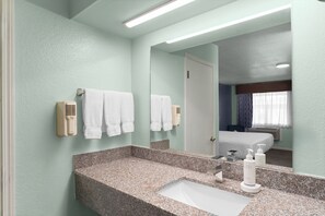 A bathroom with a granite countertop, a white sink, and two wall-mounted hair dryers.