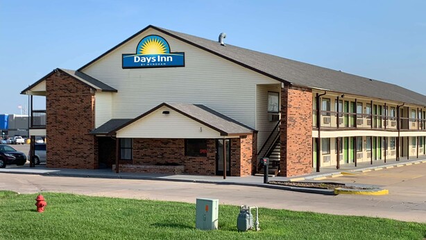 Un Days Inn by Wyndham con fachada de ladrillo, entrada cubierta y estacionamiento.